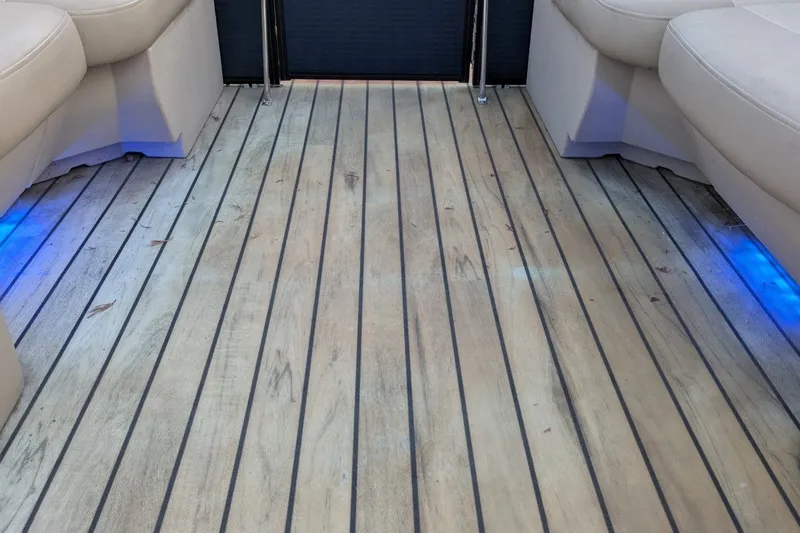 Slide: The Image of Interior view of 2017 Manitou 23 Aurora VP boat with wood flooring and blue LED lights. - 9