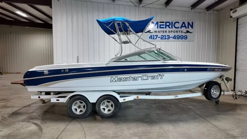 The Image of A 2000 MasterCraft MariStar 230 on a trailer inside a warehouse. - 1