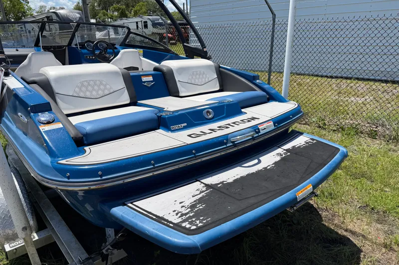 Slide: The Image of 2018 Glastron GTS 187 boat with blue and white seating, parked on a trailer. - 2