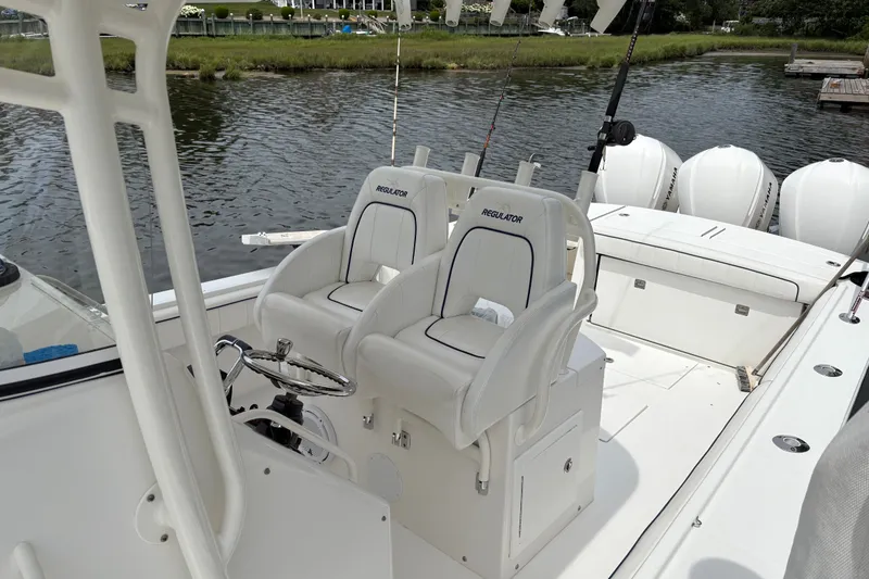 Slide: The Image of 2016 Regulator 34 boat interior with dual seats and fishing rods by the water. - 12
