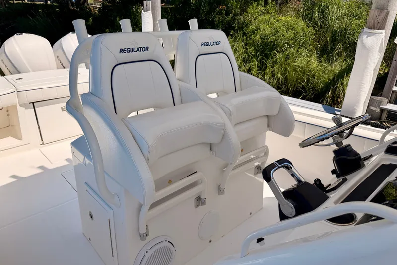 Slide: The Image of 2016 Regulator 34 boat helm with dual white cushioned seats and steering wheel. - 22