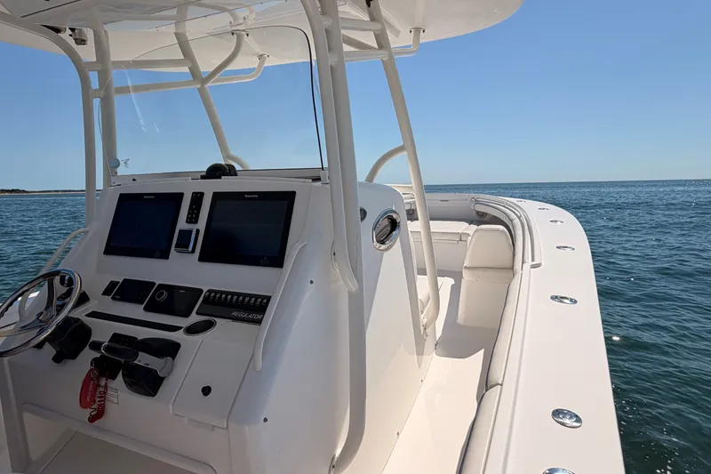Slide: The Image of 2016 Regulator 34 boat dashboard with dual screens, steering wheel, and ocean view. - 24