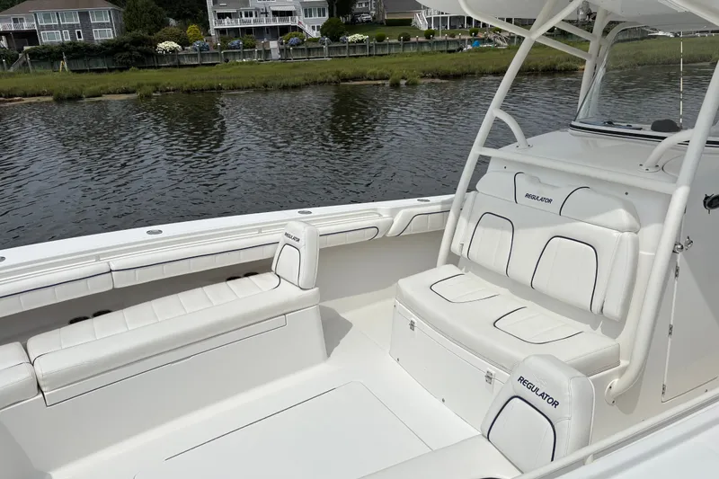 Slide: The Image of 2016 Regulator 34 boat interior with white seating, docked by waterfront homes. - 9