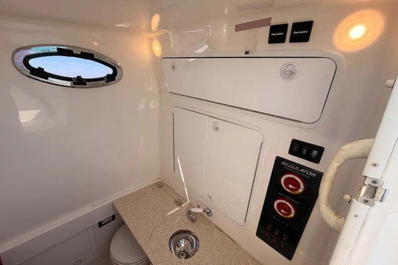 Slide: The Image of Interior of a 2016 Regulator 34 boat featuring a compact bathroom with sink and controls. - 38