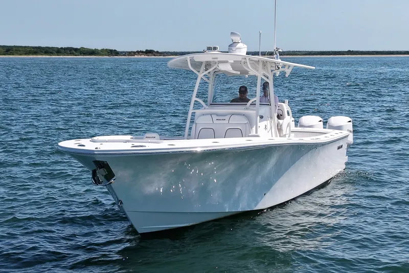 Slide: The Image of A 2016 Regulator 34 boat cruising on calm water. It features a white deck and a T-top. - 1