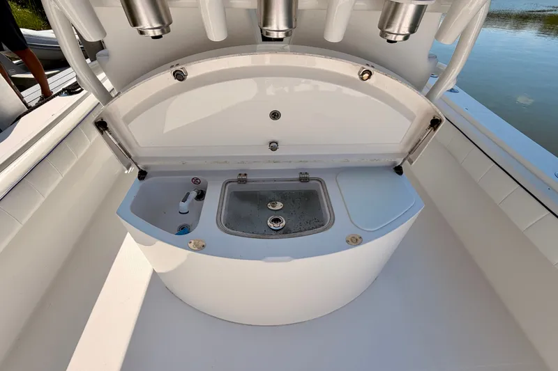 Slide: The Image of Open storage compartment on a 2016 Regulator 34 boat, featuring a sink and rod holders. - 32