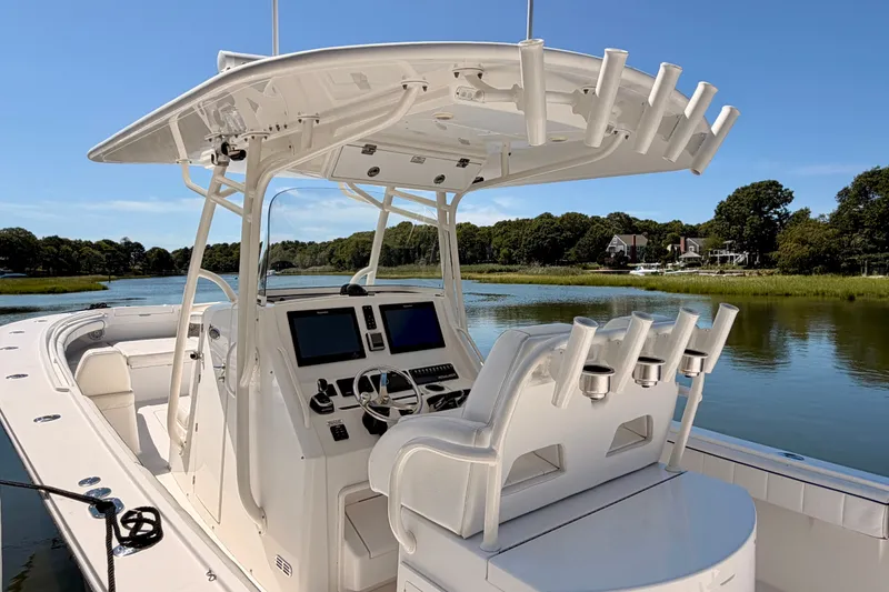 Slide: The Image of 2016 Regulator 34 boat with advanced helm, rod holders, and scenic water backdrop. - 23