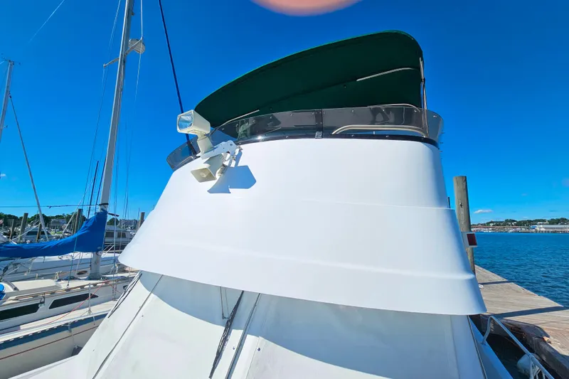 Slide: The Image of 2001 Mainship 39 Trawler docked, featuring a green canopy and clear blue sky. - 10
