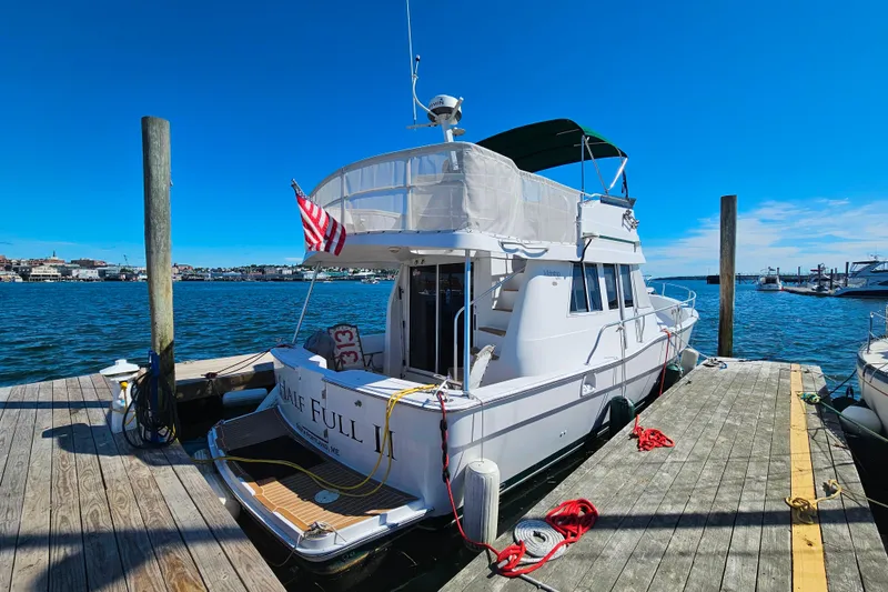 Slide: The Image of 2001 Mainship 39 Trawler docked at marina, featuring American flag and clear blue sky. - 6