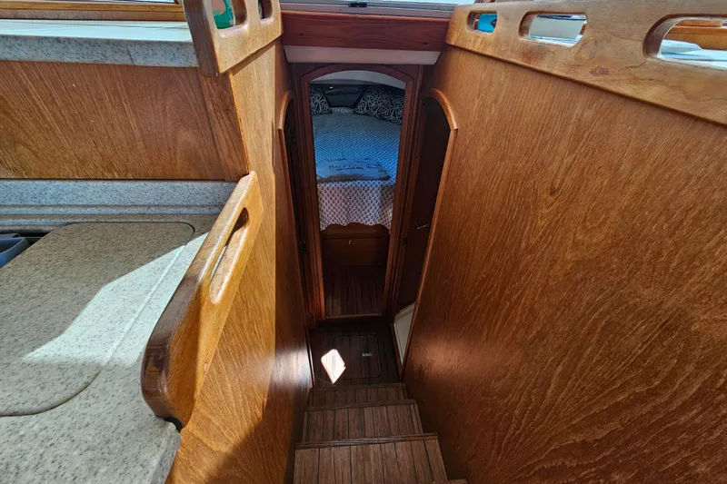 Slide: The Image of Interior view of 2000 Mainship 39 Trawler, featuring wooden stairs and cozy cabin. - 47