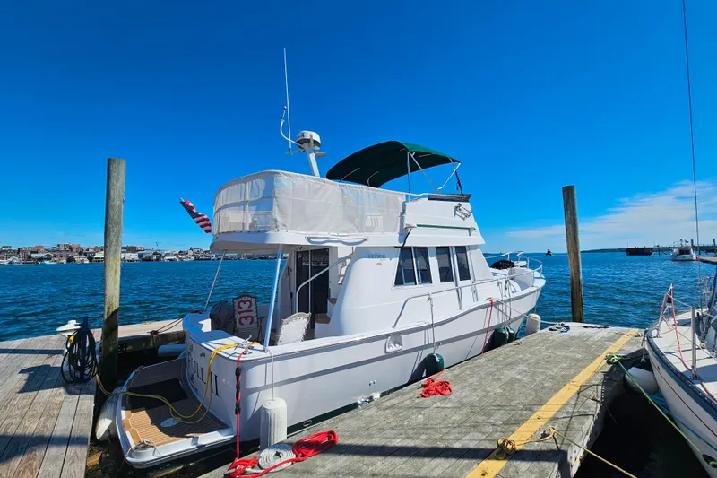 The Image of 2001 Mainship 39 Trawler docked at a marina under clear blue skies. - 0