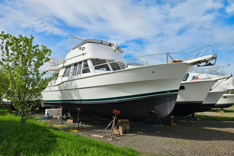 Slide: The Image of 2000 Mainship 39 Trawler on stands, surrounded by greenery and blue sky. - 55