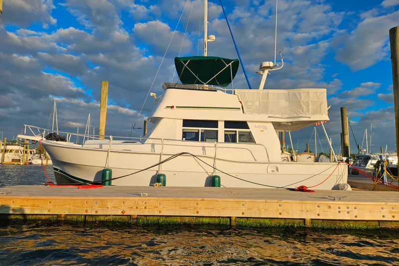 Slide: The Image of 2001 Mainship 39 Trawler docked at marina under partly cloudy sky. - 1