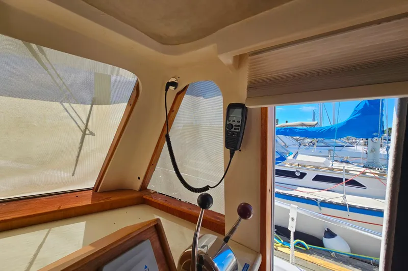 Slide: The Image of Interior view of a 2000 Mainship 39 Trawler, showcasing helm controls and marina backdrop. - 34