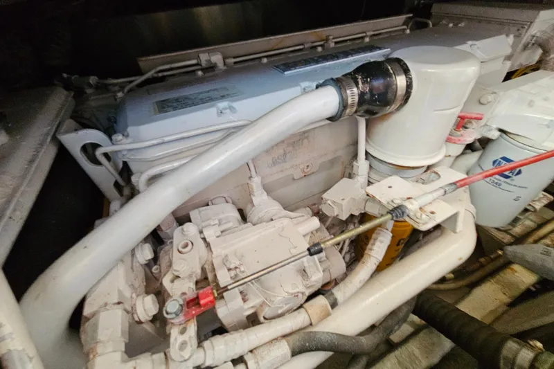 Slide: The Image of Engine compartment of a 2000 Mainship 39 Trawler, showcasing mechanical components and hoses. - 24