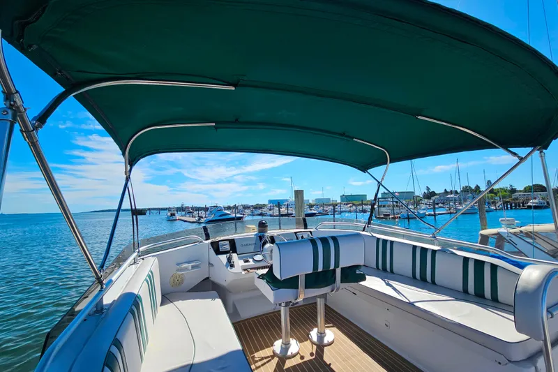Slide: The Image of 2000 Mainship 39 Trawler with green canopy, docked in a scenic marina. - 31
