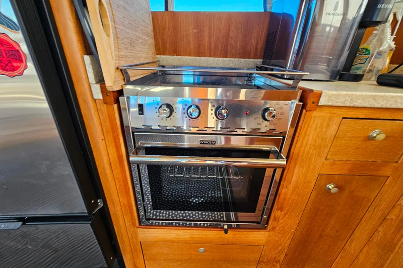 Slide: The Image of Modern kitchen oven in 2000 Mainship 39 Trawler, featuring stainless steel design and wooden cabinetry. - 41
