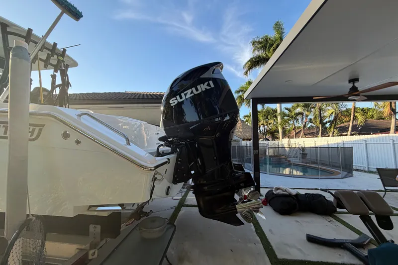 Slide: The Image of 2023 Sea Tech 33 boat with Suzuki outboard motor, parked near a poolside patio. - 1