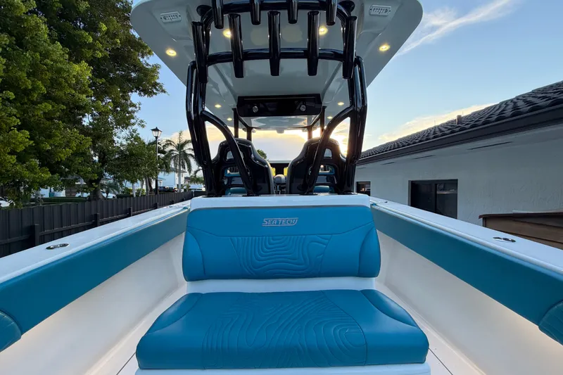 Slide: The Image of 2023 Sea Tech 33 boat interior with blue seating, illuminated canopy, and scenic background. - 26