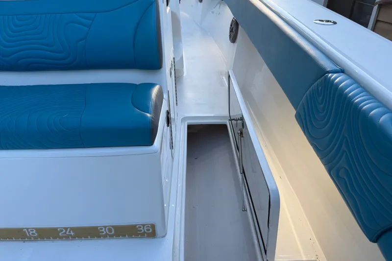 Slide: The Image of 2023 Sea Tech 33 boat interior with blue cushioned seating and open storage compartment. - 24