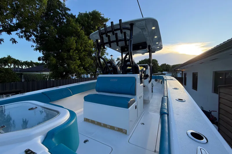 Slide: The Image of 2023 Sea Tech 33 boat with blue seating, docked at sunset near trees and a house. - 13