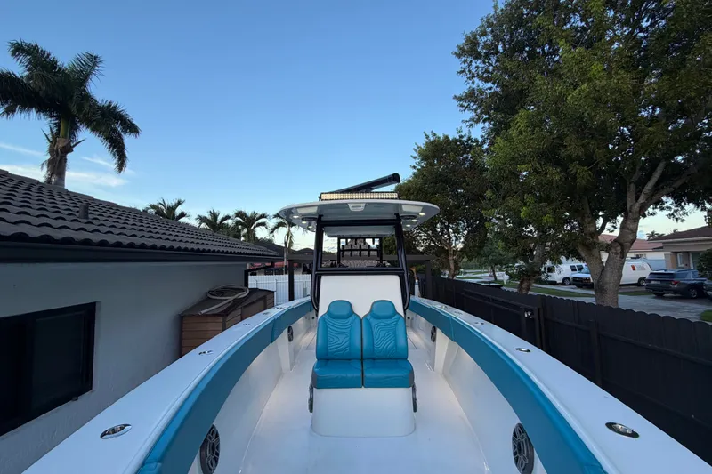 Slide: The Image of 2023 Sea Tech 33 boat with blue seating, docked near palm trees and houses. - 54