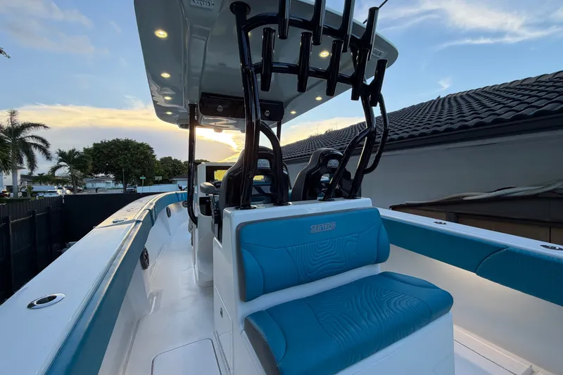 Slide: The Image of 2023 Sea Tech 33 boat with blue seating, illuminated deck, and sunset backdrop. - 23
