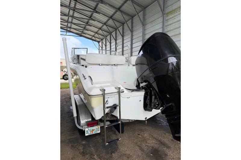Slide: The Image of 2009 Sea Fox 236 Dual Console boat under a metal shelter, rear view with outboard motor. - 12