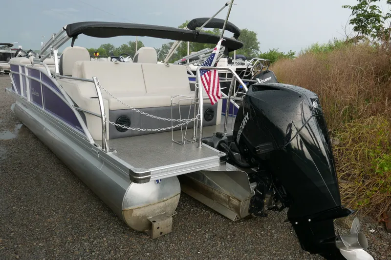 Slide: The Image of 2023 Barletta Cabrio 22UC pontoon boat with Mercury outboard motor and American flag. - 2