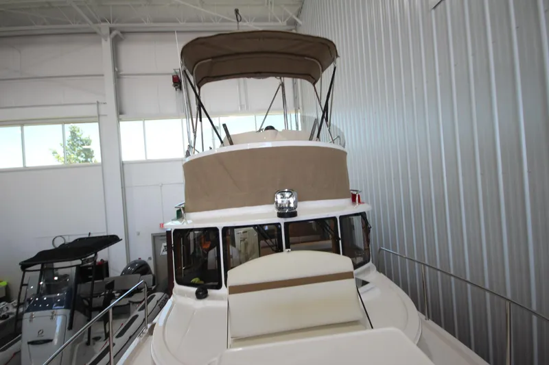 Slide: The Image of 2026 Ranger Tugs R-31 CB boat in indoor storage, featuring a covered upper deck. - 63
