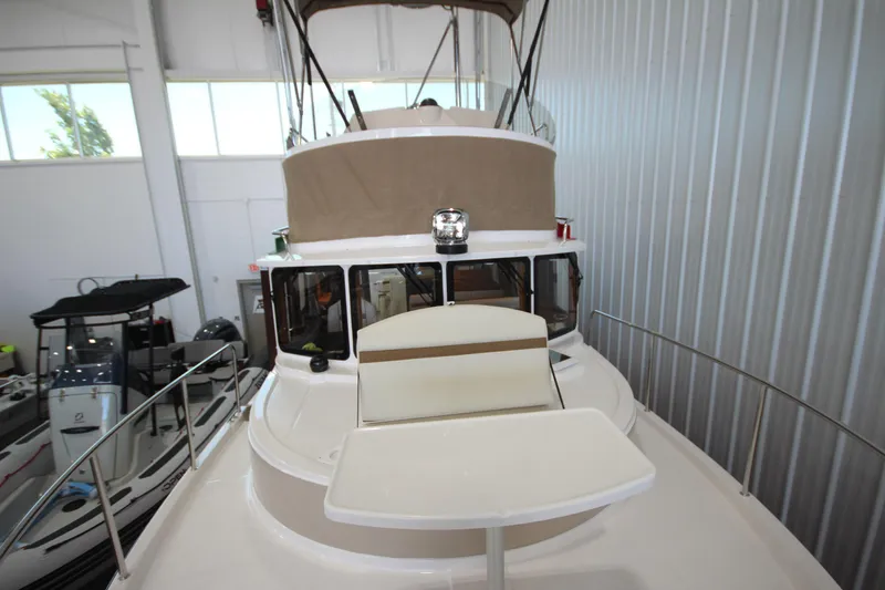 Slide: The Image of 2026 Ranger Tugs R-31 CB boat interior, showcasing helm and seating area in a showroom. - 61