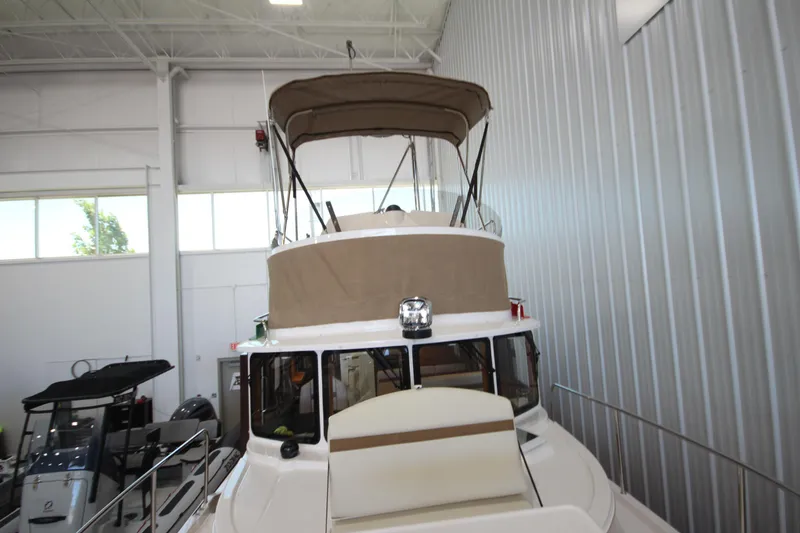 Slide: The Image of 2026 Ranger Tugs R-31 CB boat in indoor storage, showcasing upper deck and canopy. - 62