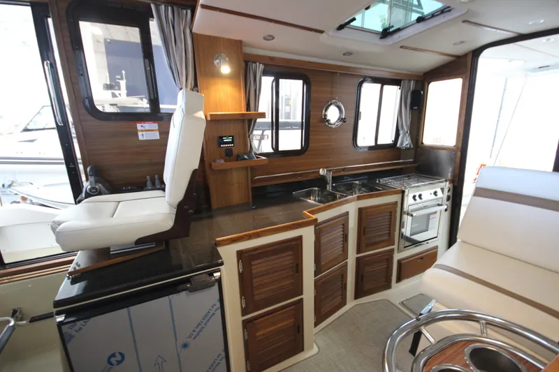 Slide: The Image of Interior of 2026 Ranger Tugs R-31 CB, featuring a compact kitchen and seating area. - 41