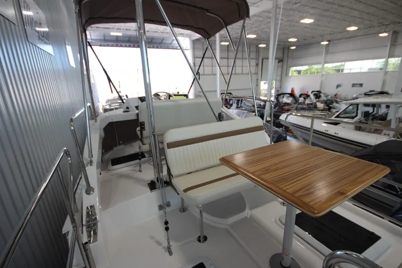 Slide: The Image of 2026 Ranger Tugs R-31 CB boat interior with seating and wooden table in a showroom. - 23