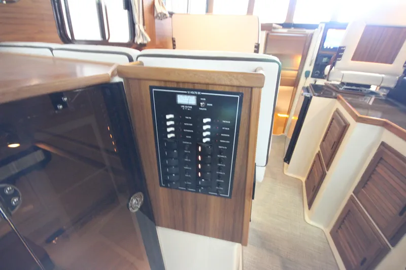 Slide: The Image of Interior of 2026 Ranger Tugs R-31 CB, featuring control panel and wooden cabinetry. - 31
