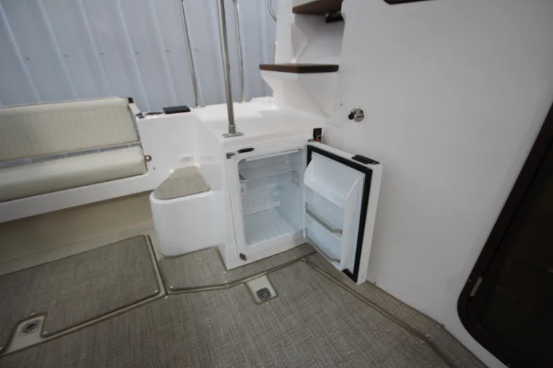 Slide: The Image of 2026 Ranger Tugs R-31 CB interior with open mini fridge and seating area. - 19