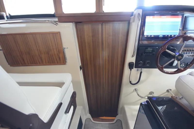 Slide: The Image of Interior of 2026 Ranger Tugs R-31 CB boat, featuring helm station and wooden cabinetry. - 50