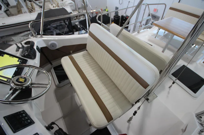 Slide: The Image of 2026 Ranger Tugs R-31 CB helm with white and brown seating, steering wheel, and controls. - 28