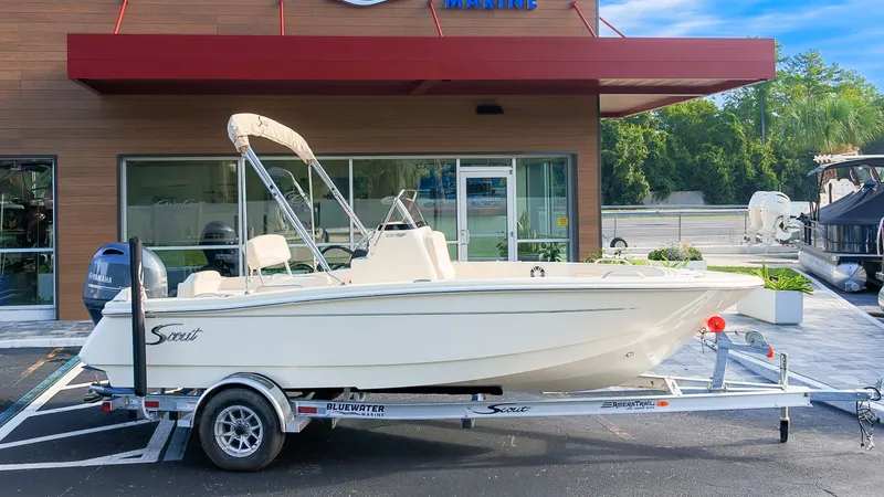 The Image of A 2027 Scout 188 Sportfish boat on a trailer in front of a modern building. - 1