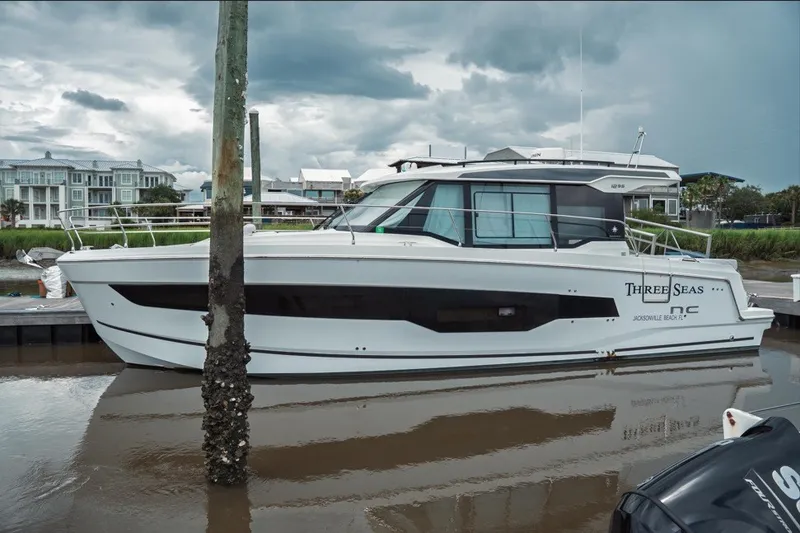 Slide: The Image of 2025 Jeanneau NC 1295 Coupe docked, showcasing sleek design and modern architecture. - 2