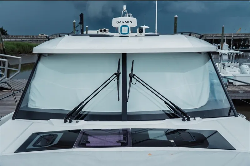 Slide: The Image of 2025 Jeanneau NC 1295 Coupe boat with Garmin equipment, docked under cloudy skies. - 9