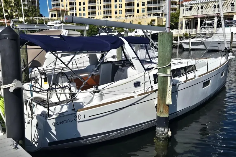 Slide: The Image of 2023 Beneteau Oceanis 38.1 yacht docked at marina, featuring sleek design and blue canopy. - 12