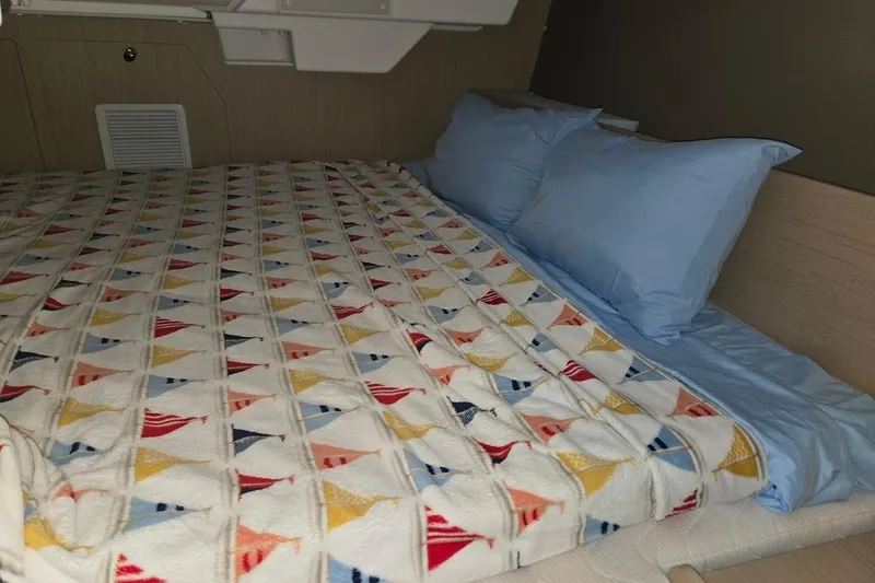 Slide: The Image of Cozy cabin bed in 2023 Beneteau Oceanis 38.1 yacht with colorful sailboat-patterned blanket. - 8