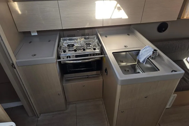 Slide: The Image of 2023 Beneteau Oceanis 38.1 yacht kitchen with stove, sink, and modern cabinetry. - 42