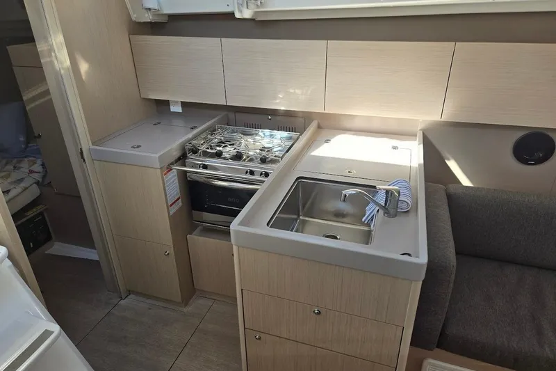 Slide: The Image of 2023 Beneteau Oceanis 38.1 yacht interior kitchen with stove, sink, and cabinets. - 44