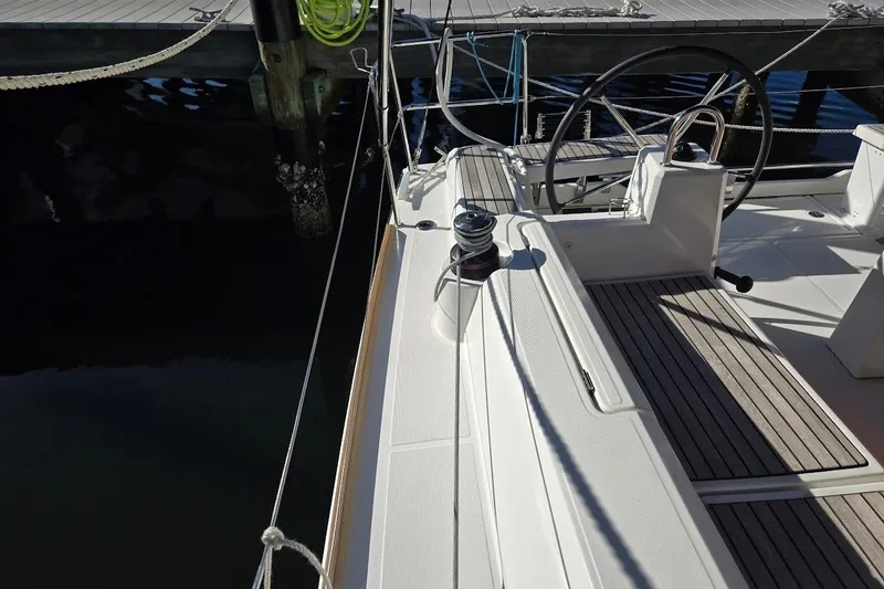 Slide: The Image of 2023 Beneteau Oceanis 38.1 sailboat deck with steering wheel and winch. - 80