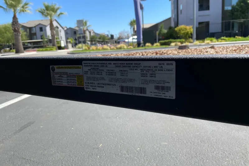 Slide: The Image of Label on 2026 Tracker Targa V-19 Combo trailer, outdoors with palm trees and buildings. - 84
