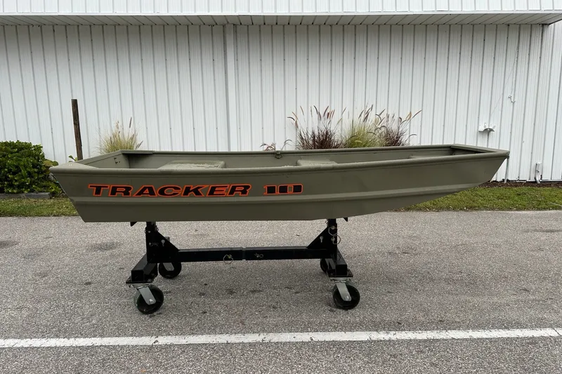 The Image of 2026 Tracker Grizzly 10 Jon boat on wheeled stand, outdoors near white building. - 0
