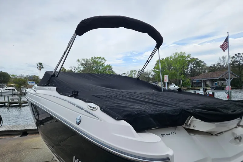 Slide: The Image of 2012 Monterey 244 FS boat with black cover docked near waterfront homes. - 25