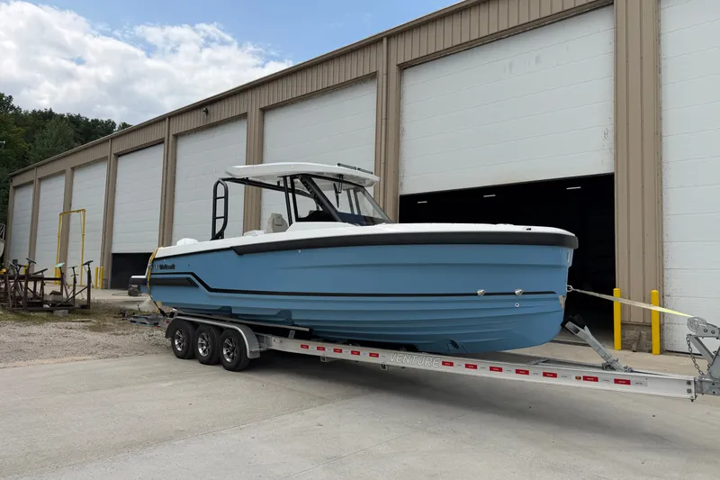 Slide: The Image of 2027 Wellcraft 28 T-Top boat on trailer outside industrial building. - 2